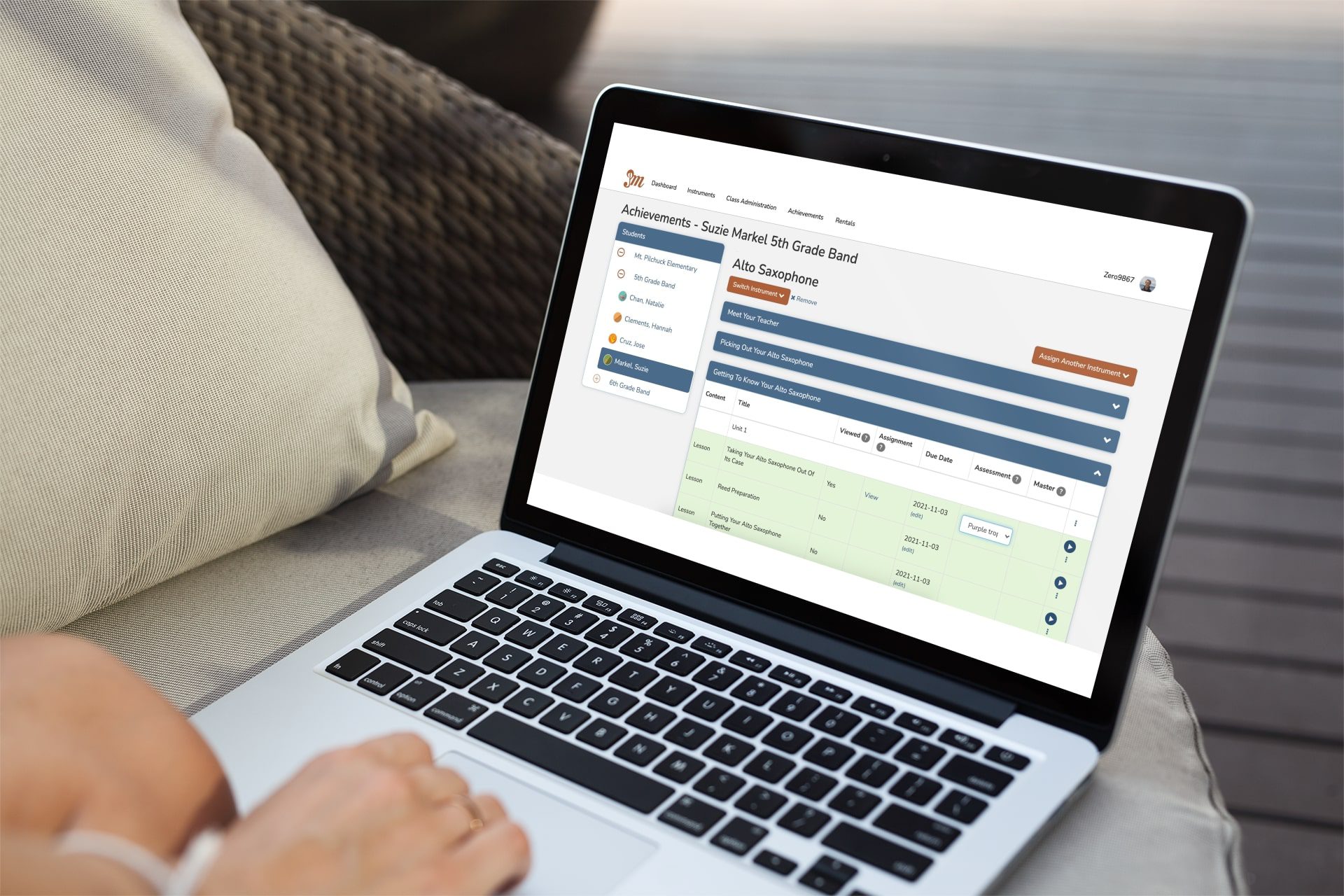 mockup-of-a-woman-using-a-macbook-at-home-2330-el1 looking at the achievements for learning to play music online with Practicing musician Music Education Platform